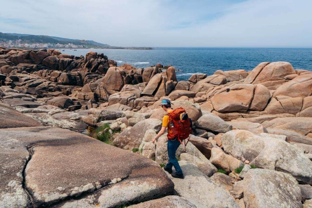 Hiking across boulders, Lighthouse Way, Spain